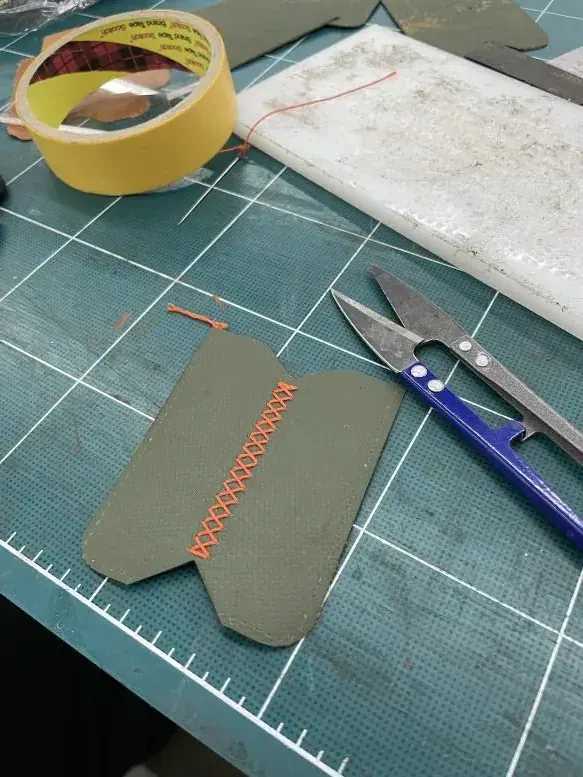 재단한 원단에 주황 실로 교차 스티치를 넣는 첫 시제품